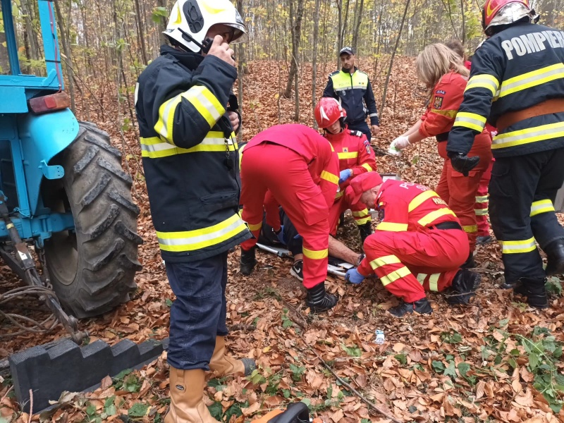 VIDEO. FOTO. Tată și fiu la un pas de moarte în pădure: un tractor s-a răsturnat peste ei